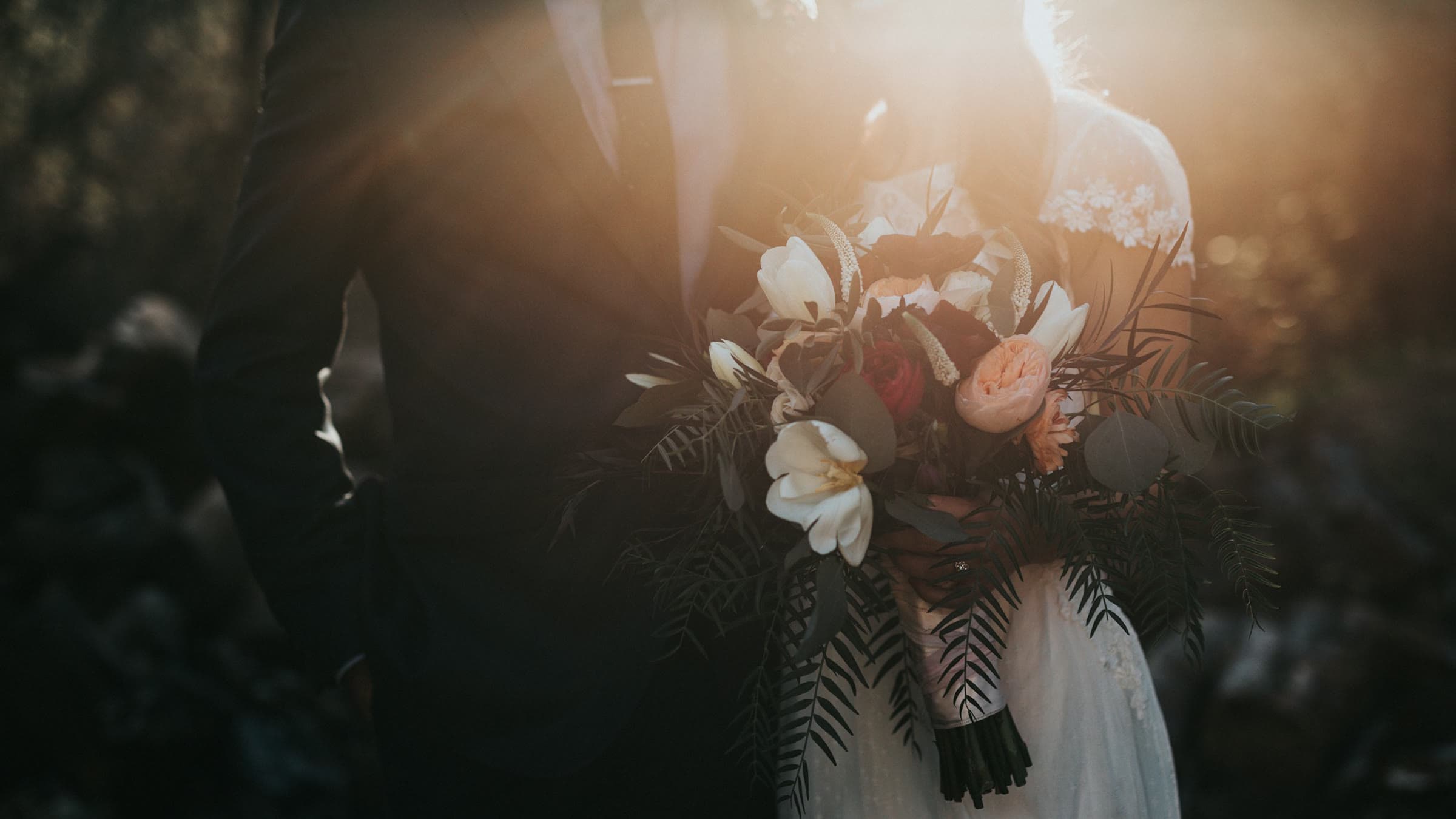 Newlyweds walking hand in hand through a garden, still frame from a wedding film